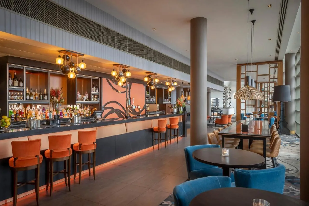 a bar in a restaurant with orange chairs and tables at Clayton Hotel Birmingham in Birmingham